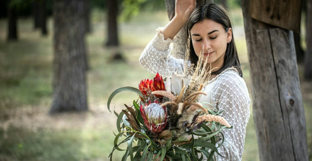 Portrait of an attractive young woman with a bouquet of exotic protea flowers.